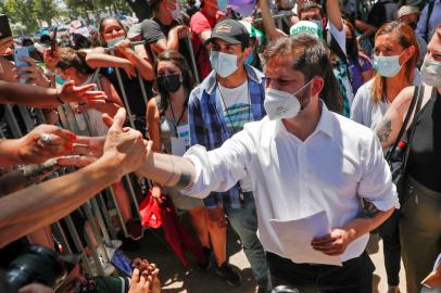 Chilean presidential candidate Gabriel Boric, of the Apruebo Dignidad party, shakes hands with supporters during a rally in Santiago, on December 16, 2021, ahead of the presidential run-off election. - Far-right fiscal conservative Jose Antonio Kast and left-wing former student activist Gabriel Boric will vie to become president of Chile next month in a run-off election, two years after anti-inequality protests that set the country on the path to constitutional change. (Photo by JAVIER TORRES / AFP)<!-- NICAID(14970024) -->