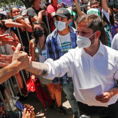 Chilean presidential candidate Gabriel Boric, of the Apruebo Dignidad party, shakes hands with supporters during a rally in Santiago, on December 16, 2021, ahead of the presidential run-off election. - Far-right fiscal conservative Jose Antonio Kast and left-wing former student activist Gabriel Boric will vie to become president of Chile next month in a run-off election, two years after anti-inequality protests that set the country on the path to constitutional change. (Photo by JAVIER TORRES / AFP)<!-- NICAID(14970024) -->