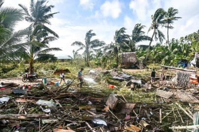 Residents walk past their destroyed homes in Hernani town, Eastern Samar province on December 17, 2021, a day after Super Typhoon Rai pummelled the southern and central regions of the Philippines. (Photo by Alren BERONIO / AFP)<!-- NICAID(14970753) -->