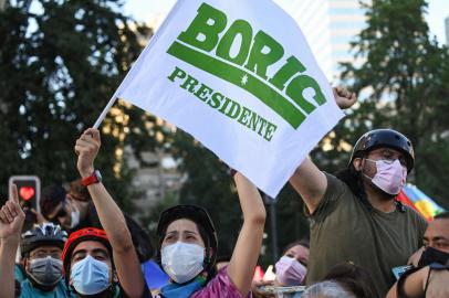 Supporters of Chilean President elect Gabriel Boric, from the Apruebo Dignidad party, celebrate following the official results of the runoff presidential election, in Santiago, on December 19, 2021. - Leftist lawmaker Gabriel Boric, 35, on Sunday became Chiles youngest-ever president on promises of installing a welfare state in one of the worlds most unequal countries. (Photo by MARTIN BERNETTI / AFP)<!-- NICAID(14972235) -->