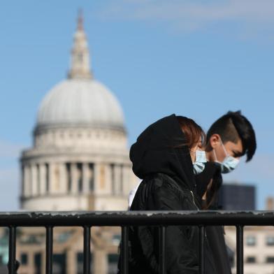 Pedestrians wearing face masks walk along a bridge with St Pauls Cathedral in the background in London on March 12, 2020. - The British government was expected Thursday to implement the second phase of its plan to deal with the coronavirus outbreak but rejected calls for parliament to be suspended after an MP tested positive. (Photo by ISABEL INFANTES / AFP)<!-- NICAID(14448926) -->