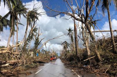 Tricycles speeds past fallen coconut trees at the height of Super Typhoon Rai along a highway in Del Carmen town, Siargao island on December 20, 2021, days after Super Typhoon Rai hit the province. (Photo by Roel CATOTO / AFP)<!-- NICAID(14973267) -->