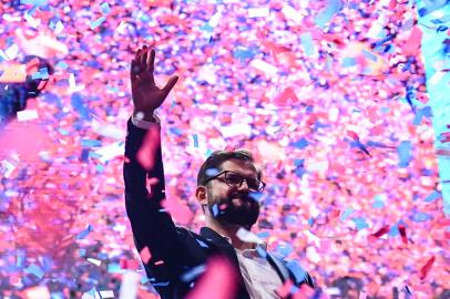 Chilean president-elect Gabriel Boric waves at supporters after delivering a speech, in Santiago, on December 19, 2021. - The streets of Santiago exploded in celebration Sunday after leftist millennial Gabriel Boric was declared Chiles new president with an unexpectedly large victory over his far-right rival in a polarizing race. Boric, 35, garnered nearly 56 percent of the vote compared to 44 percent for ultra-conservative Jose Antonio Kast, who congratulated the president-elect on Twitter even before the final result was known. (Photo by MARTIN BERNETTI / AFP)<!-- NICAID(14974835) -->