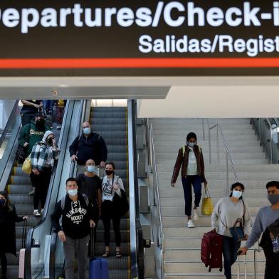 MIAMI, FLÓRIDA - 28 DE DEZEMBRO: Os viajantes fazem o seu caminho através do Aeroporto Internacional de Miami em 28 de dezembro de 2021 em Miami, Flórida. No fim de semana do feriado, os casos de COVID-19 nos EUA atingiram seu nível mais alto em quase um ano. Mais de 2.000 voos foram cancelados no fim de semana, pois as companhias aéreas lidaram com o aumento de casos COVID-19 devido à variante Omicron. Joe Raedle / Getty Images / AFP (Foto de JOE RAEDLE / GETTY IMAGES AMÉRICA DO NORTE / Getty Images via AFP)<!-- NICAID(14984029) -->