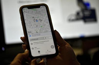 A woman checks the Uber transport application on her mobile phone after authorities ordered its suspension in Colombia, in Bogota on December 20, 2019. (Photo by Juan BARRETO / AFP)<!-- NICAID(14366948) -->