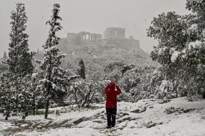 A man takes photograph of snow-covered Acropolis in Athens during heavy snowfall  on January 24, 2022. - Schools are closed in greatest Athens area, as Greece exepriences a cold weather front with heavy snowfalls and very low temperatures. (Photo by Louisa GOULIAMAKI / AFP)<!-- NICAID(14997145) -->