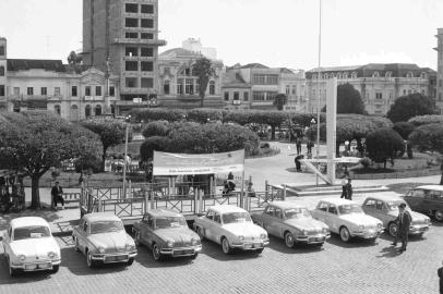 Exposição do modelo Renault Dauphine na Rua Sinimbu, em frente à antiga Praça Rui Barbosa (Dante Alighieri)  Veículos eram revendidos pela Brasdiesel, que costumava expor os úlitmos veículos recebidos no centro de Caxias do Sul. Ao fundo, a construção do Condomínio Galeria Auto João Muratore, o popular Caixa de Fósforo. Data: 1959.<!-- NICAID(14995936) -->