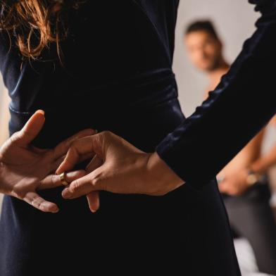 Selective focus of woman with hands behind back taking off wedding ring near shirtless man in bedroomFonte: 372938179<!-- NICAID(15000326) -->