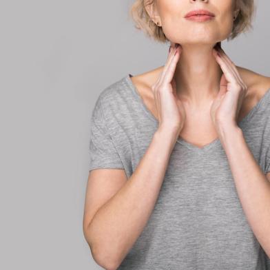 Female checking thyroid gland by herself. Close up of woman in white t- shirt touching neck with red spot. Thyroid disorder includes goiter, hyperthyroid, hypothyroid, tumor or cancer. Health care.28/04/2021- Pescoço, garganta, mulher. Foto: burdun  / stock.adobe.comFonte: 237394541<!-- NICAID(14768697) -->