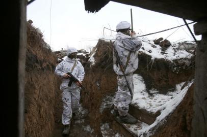 An Ukrainian soldier watches through spyglass as other one stands near in a trench on the frontline with the Russia-backed separatists near Verkhnetoretskoye village, in the Donetsk region on February 1, 2022. (Photo by Anatolii STEPANOV / AFP)<!-- NICAID(15004966) -->