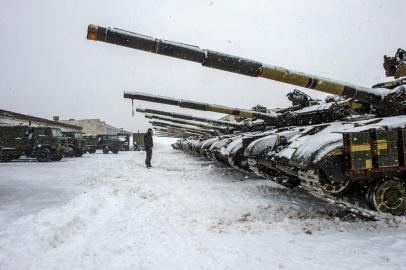 Um soldado das Forças Militares Ucranianas fica na frente de tanques da 92ª brigada mecanizada separada das Forças Armadas Ucranianas, estacionada em sua base perto da vila de Klugino-Bashkirivka, na região de Kharkiv, em 31 de janeiro de 2022. - Os tanques precisam restaurar sua capacidade de combate depois de completar uma missão de combate no leste da Ucrânia devastado pela guerra. (Foto de Sergey BOBOK/AFP)<!-- NICAID(15003216) -->