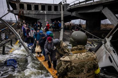 Evacuados atravessam uma ponte destruída enquanto fogem da cidade de Irpin, a noroeste de Kiev, em 7 de março de 2022. - A Ucrânia rejeitou a oferta de Moscou de criar corredores humanitários de várias cidades bombardeadas na segunda-feira, depois que surgiram algumas rotas que levariam refugiados para a Rússia ou Bielorrússia. A proposta russa de passagem segura de Kharkiv, Kiev, Mariupol e Sumy veio depois que civis ucranianos aterrorizados foram atacados em tentativas anteriores de cessar-fogo. (Foto de Dimitar DILKOFF/AFP)<!-- NICAID(15035115) -->