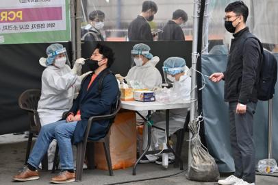 A medical worker (L) takes a nasal swab sample from a man at a Covid-19 coronavirus testing centre in Seoul on March 17, 2022, after South Koreas daily infections rose sharply to hit a new high of over 600,000. (Photo by Jung Yeon-je / AFP)<!-- NICAID(15043434) -->