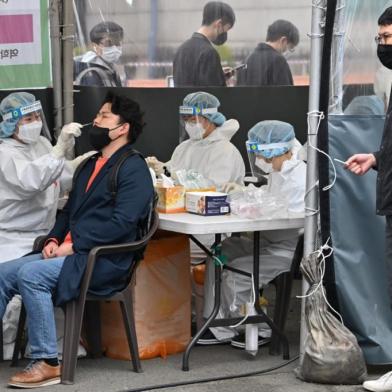 A medical worker (L) takes a nasal swab sample from a man at a Covid-19 coronavirus testing centre in Seoul on March 17, 2022, after South Koreas daily infections rose sharply to hit a new high of over 600,000. (Photo by Jung Yeon-je / AFP)<!-- NICAID(15043434) -->