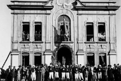 Associada imediatamente ao prédio da esquina da Av. Júlio de Castilhos com a Rua Marquês do Herval, a sede social do Clube Juvenil ¿transitou¿ por outros endereços até ser inaugurada ali, em 8 de setembro de 1928. Um deles, o terceiro, foi o espaço inaugurado há 110 anos, em 1912. Falamos do prédio localizado na esquina das ruas Visconde de Pelotas e Os Dezoito do Forte, ainda quando esta chamava-se Andrade Pinto. Na foto, os atletas Antenor Zanoni (12), Heitor Ferrareto (13) e Izidio Reali (1) defronte ao Clube Juvenil após concluírem a corrida festiva ao aniversário de sete anos do clube, em 18 de junho de 1912. O Juvenil foi fundado em 1905. Os atletas saíram do Clube Aliança, em Bento, rumo ao Juvenil, em Caxias.<!-- NICAID(15041802) -->