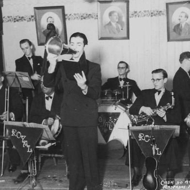 Royal Jazz Band, com Alcides Gonçalves de crooner, antes da chegada do microfone na cidade. Até então, os cantores usavam megafones de lata. A Royal Jazz Band, dos anos 1920, depois abrasileirou-se e mudou o nome para Orquestra Rojabá. Imagem do livro ¿Porto Alegre: uma biografia musical¿, de Arthur de Faria.<!-- NICAID(15046539) -->