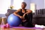 Senior Black woman sitting on floor with exercise equipmentFonte: 72390857<!-- NICAID(15046894) -->