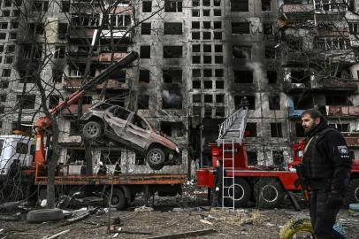 Um guindaste remove um carro arruinado da frente de um prédio de apartamentos destruído depois que ele foi bombardeado no noroeste do distrito de Obolon, em Kiev, em 14 de março de 2022. - Duas pessoas foram mortas em 14 de março de 2022, enquanto vários bairros da capital ucraniana, Kiev foi alvo de bombardeios e ataques de mísseis, disseram autoridades da cidade, depois que os militares russos invadiram a Ucrânia em 24 de fevereiro de 2022. (Foto de Aris Messinis / AFP)<!-- NICAID(15041009) -->