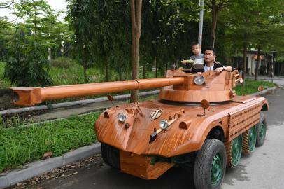 Truong Van Dao and his son ride in a wooden tank made from the conversion of an old minibus in a residential area in Bac Ninh province on March 28, 2022. - A Vietnamese father spent hundreds of hours, investing thousands, to convert an old van into a wooden tank for his son -- an unusual hobby in a country once ravaged by war. (Photo by Nhac NGUYEN / AFP)Editoria: LIFLocal: Bac NinhIndexador: NHAC NGUYENSecao: transportFonte: AFPFotógrafo: STF<!-- NICAID(15053954) -->