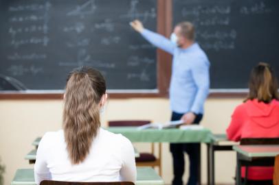 Teacher and his students wearing protective face mask in the classroom. Social distanting and classroom safety during coronavirus epidemicFonte: 421265333<!-- NICAID(15057405) -->