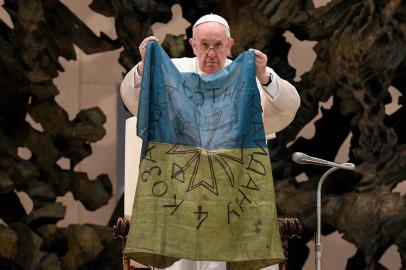 This photo taken and handout by The Vatican Media on April 6, 2022 shows Pope Francis holding a flag of Ukraine that comes from the city of Bucha, one of the areas around Ukraines capital from which Russian troops have withdrawn and where dozens of bodies in civilian clothing have been found, during the weekly general audience on April 6, 2022 at Paul-VI hall in The Vatican. (Photo by Handout / VATICAN MEDIA / AFP) / RESTRICTED TO EDITORIAL USE - MANDATORY CREDIT AFP PHOTO / VATICAN MEDIA - NO MARKETING - NO ADVERTISING CAMPAIGNS - DISTRIBUTED AS A SERVICE TO CLIENTS<!-- NICAID(15061078) -->