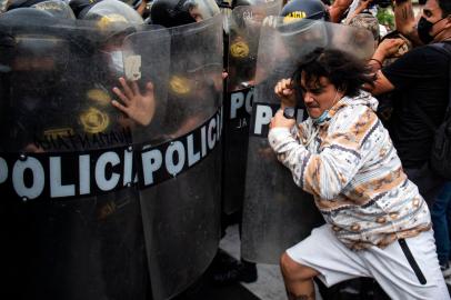 People clash with riot police during a protest against the governement of Perus President Pedro Castillo, in Lima on April 05, 2022 - Peruvian President Pedro Castillo announced the end of a curfew in the capital Lima aimed at containing protests against rising fuel prices following crisis talks with Congress. (Photo by ERNESTO BENAVIDES / AFP)<!-- NICAID(15062670) -->