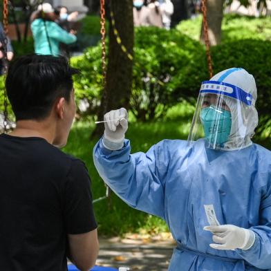 A health worker conducts a swab test for the Covid-19 coronavirus at a residential compound during the second stage of a pandemic lockdown in Jing an district in Shanghai on April 6, 2022. (Photo by HECTOR RETAMAL / AFP)<!-- NICAID(15064721) -->