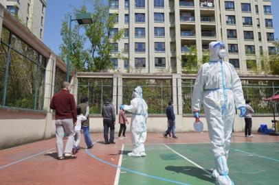 Community volunteers wearing personal protective equipment organize residents for a Covid-19 coronavirus test in a compound during a Covid-19 lockdown in Pudong district in Shanghai on April 17, 2022. (Photo by LIU JIN / AFP) / China OUT<!-- NICAID(15071251) -->