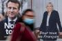 A woman passes by electoral campaign posters of French President and La Republique en Marche (LREM) party candidate for re-election Emmanuel Macron (L) and French far-right party Rassemblement National (RN) presidential candidate Marine Le Pen in Savenay, western France on April 19, 2022. - Emmanuel Macron won 27.85 percent of votes in the first round of Frances presidential election, while far-right veteran Marine Le Pen scored 23.15 percent, according to final results from the interior ministry on April 18, 2022. (Photo by Loic VENANCE / AFP)<!-- NICAID(15072338) -->