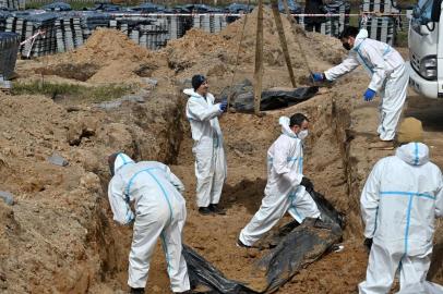 Workers exhume bodies from a mass grave in Bucha, north-west of Kyiv, on April 14, 2022. - French gendarmes and forensic doctors have arrived in Ukraine to help investigate the discovery of scores of bodies in civilian clothing scattered in Bucha and other towns around Kyiv after Russias withdrawal from the region. Ukraine says it has discovered 1,222 bodies in Bucha and other towns. (Photo by Sergei SUPINSKY / AFP)<!-- NICAID(15069117) -->