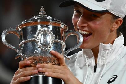 Polands Iga Swiatek poses with the trophy after winning against US Coco Gauff at the end of their womens single final match on day fourteen of the Roland-Garros Open tennis tournament at the Court Philippe-Chatrier in Paris on June 4, 2022. - Iga Swiatek cruised to her second French Open title by dominating teenager Coco Gauff in the final as the world number one claimed her 35th successive victory. (Photo by Anne-Christine POUJOULAT / AFP)<!-- NICAID(15115585) -->