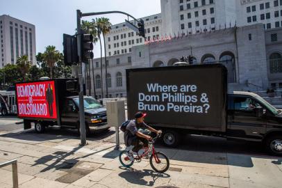 People walk by a truck with messages about British journalist Dom Phillips and Brazilian Indigenous affairs specialist Bruno Pereira, who are missing in the Amazon rainforest, in front of LA City Hall in Los Angeles, California, on June 08, 2022. - Leaders from North and South America are gathering in Los Angeles for the ninth Summit of the Americas. (Photo by Apu GOMES / AFP)Editoria: POLLocal: Los AngelesIndexador: APU GOMESSecao: diplomacyFonte: AFPFotógrafo: STF<!-- NICAID(15119199) -->