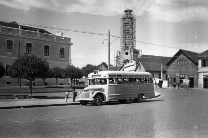 Trecho da Avenida Júlio de Castilhos no enntroncamento com a Feijó Júnior, no bairro São Pelegrino, por volta de 1950. No local vê-se a Praça João Pessoa, a antiga sede do Colégio São Carlos e a Igreja de São Pelegrino sendo construída. À direita, meio cortada, a casa do morador e dentista Aparício Postali. <!-- NICAID(14026004) -->