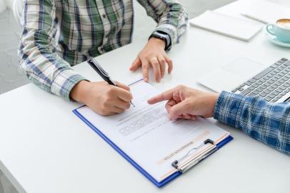 Woman employee writing a letter of resignation on the white table. The concept for forced resign.Woman employee writing a letter of resignation on the white table. The concept for forced resign.Fonte: 220624117<!-- NICAID(15150493) -->