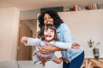 Mother playfully swinging her little daughter in the airMãe brincando balançando sua filha no ar enquanto se divertem juntos em casaFonte: 295880665<!-- NICAID(14316715) -->