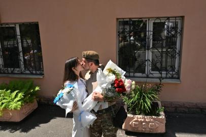 Ukrainian serviceman Vitaliy (R), 25, kisses his wife outside one of the city register offices just after the wedding ceremony in Kyiv on July 23, 2022. - Since the Russian invasion of Ukraine on February 24, 2022, Ukraine is experiencing an unprecedented rush to the altar: 9,120 marriages have been registered in 5 months in Kyiv, compared to the 1,110 registered during the same period in 2021. (Photo by Sergei SUPINSKY / AFP)Editoria: WARLocal: KyivIndexador: SERGEI SUPINSKYSecao: warFonte: AFPFotógrafo: STF<!-- NICAID(15160660) -->