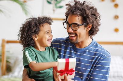 Cheerful ethnic  father and son celebrating Fathers Day together at home*A PEDIDO DE ADRIANA BARBOZA* Happy african american family father with excited child son hugging smiling  while celebrating Fathers day together at home. Boy congratulating giving dad gift box - Foto: JenkoAtaman/stock.adobe.comFonte: 494465492<!-- NICAID(15169934) -->