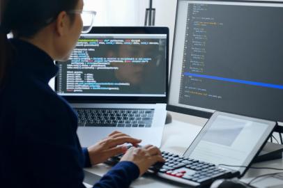 Young Asian woman, developer programmer, software engineer, IT support, wearing glasses working on computer to check coding in bugging system. Back viewFonte: 500709335<!-- NICAID(15185742) -->