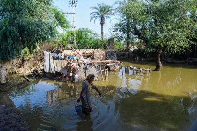 In this picture taken on August 28, 2022, Amina Khatoon carries a bucket of water to her flood-damaged house on the outskirts of Sukkur, Sindh province. - The death toll from monsoon flooding in Pakistan since June has reached 1,061, according to figures released on August 29, 2022, by the countrys National Disaster Management Authority. (Photo by Asif HASSAN / AFP)<!-- NICAID(15190881) -->