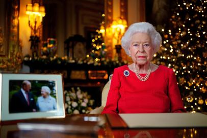 A picture released on December 23, 2021 shows Britains Queen Elizabeth II posing for a photograph as she recorded her annual Christmas Day message, with a photograph of herself and her late husband Britains Prince Philip, Duke of Edinburgh, taken in 2007 at Broadlands, to mark their Diamond Wedding Anniversary, in the White Drawing Room Windsor Castle, west of London. (Photo by Victoria Jones / POOL / AFP) / EMBARGOED UNTIL 2230 GMT on December 23, 2021.Editoria: RELLocal: Windsor CastleIndexador: VICTORIA JONESSecao: imperial and royal mattersFonte: POOLFotógrafo: STR<!-- NICAID(15200524) -->