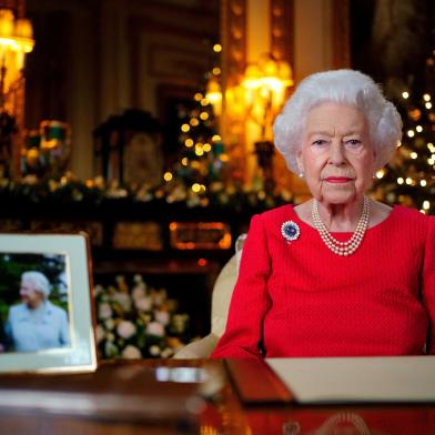 A picture released on December 23, 2021 shows Britains Queen Elizabeth II posing for a photograph as she recorded her annual Christmas Day message, with a photograph of herself and her late husband Britains Prince Philip, Duke of Edinburgh, taken in 2007 at Broadlands, to mark their Diamond Wedding Anniversary, in the White Drawing Room Windsor Castle, west of London. (Photo by Victoria Jones / POOL / AFP) / EMBARGOED UNTIL 2230 GMT on December 23, 2021.Editoria: RELLocal: Windsor CastleIndexador: VICTORIA JONESSecao: imperial and royal mattersFonte: POOLFotógrafo: STR<!-- NICAID(15200524) -->