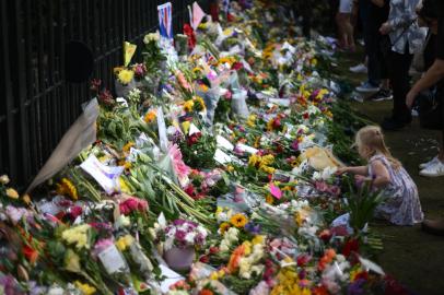 A girl place flowers in front of tributes outside the gates of Windsor Castle, west of London, on September 12, 2022, following the death of Queen Elizabeth II on Septhember 8. - The state funeral for Queen Elizabeth II will be held at Westminster Abbey in London at 11:00 am (1000 GMT) on Monday September 19, royal officials said on Saturday. (Photo by Daniel LEAL / AFP)<!-- NICAID(15203717) -->