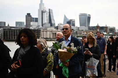 Members of the public stand in the queue, opposite the skyscrapers of the City of London, as they wait in line to pay their respects to the late Queen Elizabeth II, in London on September 15, 2022. - Queen Elizabeth II will lie in state until 0530 GMT on September 19, a few hours before her funeral, with huge queues expected to file past her coffin to pay their respects. (Photo by Marco BERTORELLO / AFP)Editoria: HUMLocal: LondonIndexador: MARCO BERTORELLOSecao: imperial and royal mattersFonte: AFPFotógrafo: STF<!-- NICAID(15206702) -->