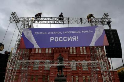 Workers fix a banner reading Donetsk, Lugansk, Zaporizhzhia, Kherson - Russia! on top of a construction installed in front of the State Historical Museum outside Red Square in central Moscow on September 29, 2022. - Russia will formally annex four regions of Ukraine its troops occupy at a grand ceremony in Moscow on September 30, the Kremlin has announced, after it suggested using nuclear weapons to defend the territories. (Photo by Natalia KOLESNIKOVA / AFP)<!-- NICAID(15221087) -->