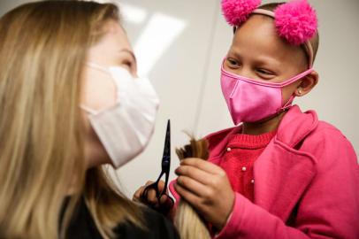 Porto Alegre, RS, Brasil, 30-09-2022: Helena (D) corta o cabelo da voluntária Gabriela Wozniak Ritter durante Trote Solidário Careca Amiga no Hospital da Criança Santo Antônio. Crianças em tratamento oncológico na instituição, com o apoio de cabeleireiros parceiros, raspam e cortam o cabelo de estudantes e profissionais da saúde no Ambulatório de Oncologia do hospital para a doação de cabelos para a ONG Cabelaço. Foto: Mateus Bruxel / Agência RBSIndexador: Mateus Bruxel<!-- NICAID(15222106) -->