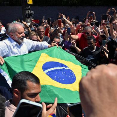 Brazilian former President (2003-2010) and candidate for the leftist Workers Party (PT) Luiz Inacio Lula da Silva unfolds a Brazilian flag while leaving the polling station during the presidential run-off election, in Sao Paulo, Brazil, on October 30, 2022. - After a bitterly divisive campaign and inconclusive first-round vote, Brazil elects its next president in a cliffhanger runoff between far-right incumbent Jair Bolsonaro and veteran leftist Luiz Inacio Lula da Silva. (Photo by NELSON ALMEIDA / AFP)Editoria: POLLocal: Sao PauloIndexador: NELSON ALMEIDASecao: electionFonte: AFPFotógrafo: STF<!-- NICAID(15249961) -->