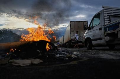 Supporters of President Jair Bolsonaro, mainly truck drivers, set a barrier on fire during a blockade on the Via Dutra BR-116 highway between Rio de Janeiro and Sao Paulo, in Volta Redonda, Rio de Janeiro state, Brazil, on October 31, 2022, as an apparent protest over Bolsonaros defeat in the presidential run-off election. - Truckers and other protesters on Monday blocked some highways in Brazil in an apparent protest over the electoral defeat of Bolsonaro to leftist Luiz Inacio Lula da Silva, authorities said. (Photo by MAURO PIMENTEL / AFP)<!-- NICAID(15252012) -->