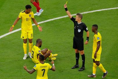 Italian referee Daniele Orsato (2nd R) shows a yellow card to Qatars midfielder Karim Boudiaf (out of frame) as Ecuadors forward Enner Valencia  (2nd L) lies on the pitch during the Qatar 2022 World Cup Group A football match between Qatar and Ecuador at the Al-Bayt Stadium in Al Khor, north of Doha on November 20, 2022. (Photo by Odd ANDERSEN / AFP)Editoria: SPOLocal: Al KhorIndexador: ODD ANDERSENSecao: soccerFonte: AFPFotógrafo: STF<!-- NICAID(15270588) -->