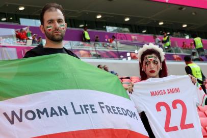 An Irans supporter with blood tears make up on her face holds a football jersey reading the name of Mahsa Amini, the 22-year-old Iranian Kurdish woman who died at the hospital after been arrested by the morality police for violating Irans strict dress code, poses with another supporter holding a flag reading Woman life freedom as they attend the Qatar 2022 World Cup Group B football match between Wales and Iran at the Ahmad Bin Ali Stadium in Al-Rayyan, west of Doha on November 25, 2022. - Iran has been rocked by more than seven weeks of nationwide protests over the death of 22-year-old Kurdish Iranian woman Masha Amini while in the custody of the Tehran morality police. (Photo by Giuseppe CACACE / AFP)Editoria: SPOLocal: DohaIndexador: GIUSEPPE CACACESecao: soccerFonte: AFPFotógrafo: STF<!-- NICAID(15276783) -->