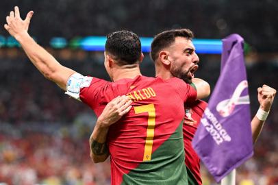 Portugals forward #07 Cristiano Ronaldo (L) celebrates scoring his teams first goal with Portugals midfielder #08 Bruno Fernandes during the Qatar 2022 World Cup Group H football match between Portugal and Uruguay at the Lusail Stadium in Lusail, north of Doha on November 28, 2022. (Photo by Kirill KUDRYAVTSEV / AFP)<!-- NICAID(15279253) -->